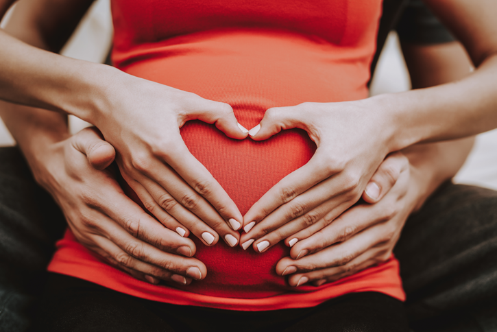 formando un corazón con las manos sobre el vientre de una mujer embarazada