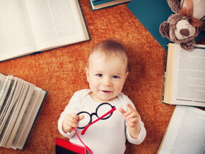 Niño de un año con anteojos rodeado de libros