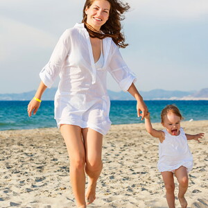 Mamá con bebe caminando y jugando en la playa cuidan de su salud