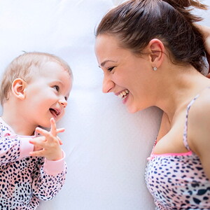 mamá-y-bebé-sonriendo-acostadas-en-la-cama