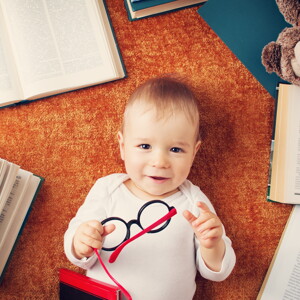 Niño de un año con anteojos rodeado de libros