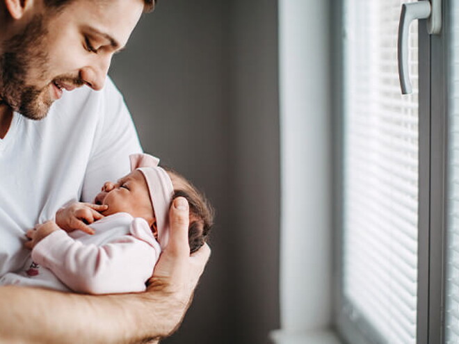 Papá alzando su bebé y revisando los granitos de su cara