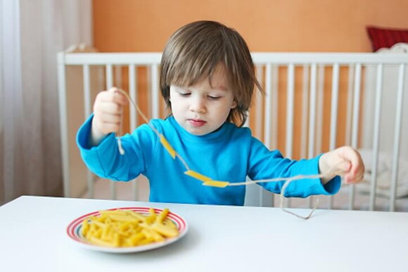 Niño ensartando obejtos en un cordón