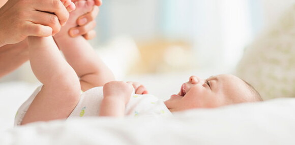 Bebé de dos meses sonriendo con las piernas levantadas