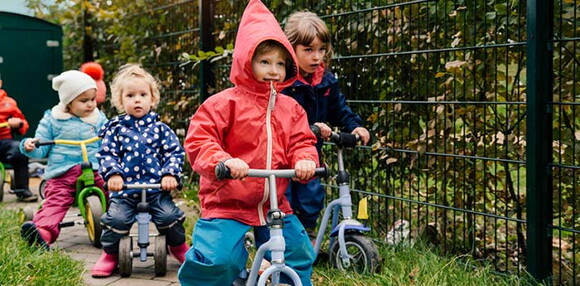 Niños montando triciclo.