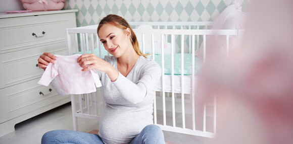 Mamá mirando la ropa de su bebé arcoíris.