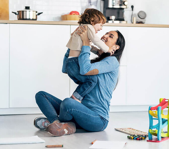 Madre jugando con su bebé en el suelo en una parte de la cocina